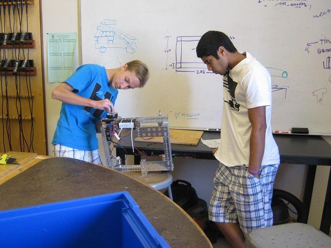 The close-knit group of seven students is building a robot to compete in the FTC challenge. Members concentrate on the adjusting the wheel as they try to get the robot to maximum operation. Photo by Howard Lee. 