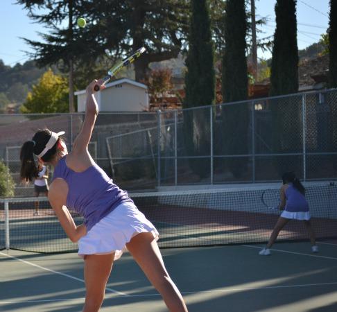 Senior Tiffany Wang slices her serve. While Wang had been unable to play for the past few weeks due to her participation in an international tai chi competition, she and her doubles partner, senior Fangfei Li, played consistently to win their match. Photo by Varsha Venkat.
