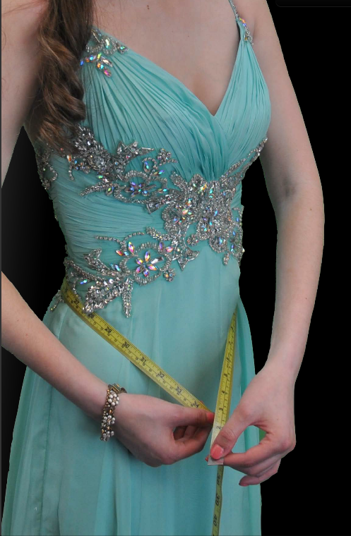 Girl in prom dress measures her waist.