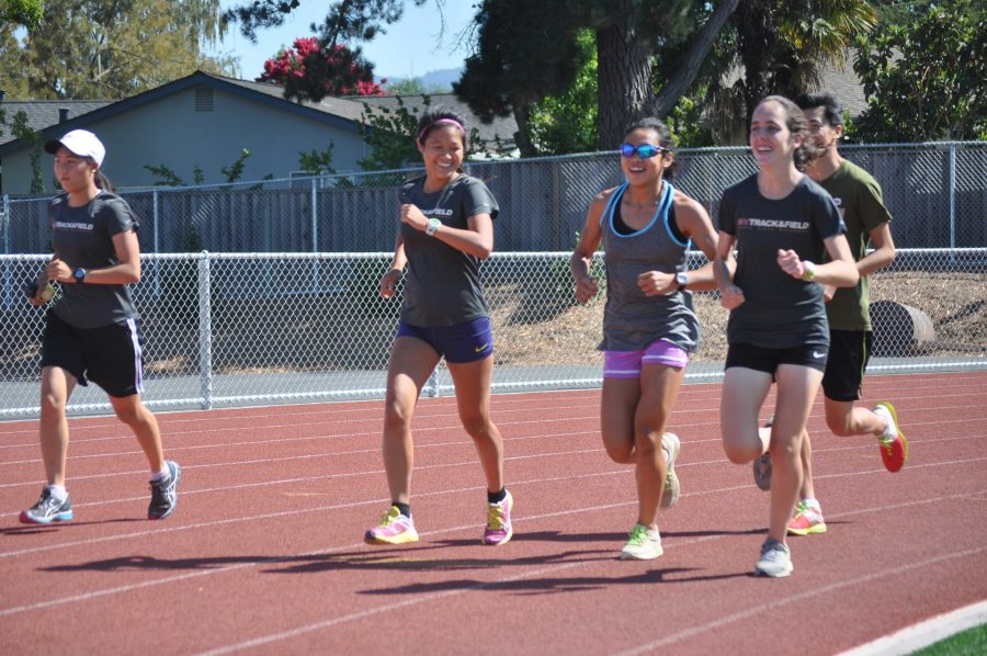 Junior Julia Chang, sophomore Madeline Yip and senior Bridget Gottlieb laugh as they do their ten minute warm up around the track together in preparation for their daily five to seven mile run. The team practices daily to increase endurance for meets. Photo by Rochish Ambati.