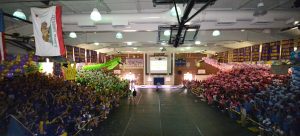 The freshmen, sophomores, juniors and seniors stand together in the gym during the 2014 Homecoming Rally. Though the rally began organized, chaos ensued near the end due to the confusion about the final results. Photo by Aditya Pimplaskar