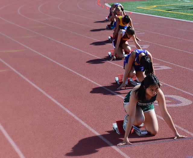 A Homestead HS athlete looks up before the start of the 100 m race. Most athletes completed a few practice starts before their event began.