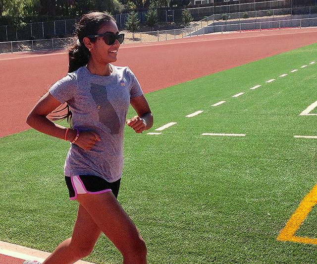 Senior Namrata Subramanian warms up around the track before practice on Aug. 31. Subramanian often listens to music when she runs alone. Photo by Kalpana Gopalkrishnan