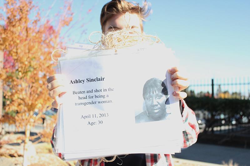 Senior Nikki Stuart, co-president of GSA, holds the banner that they will display during the vigil. The banner has the photos and stories of transgender people who were murdered or committed suicide. Photo by Sneha Gaur.