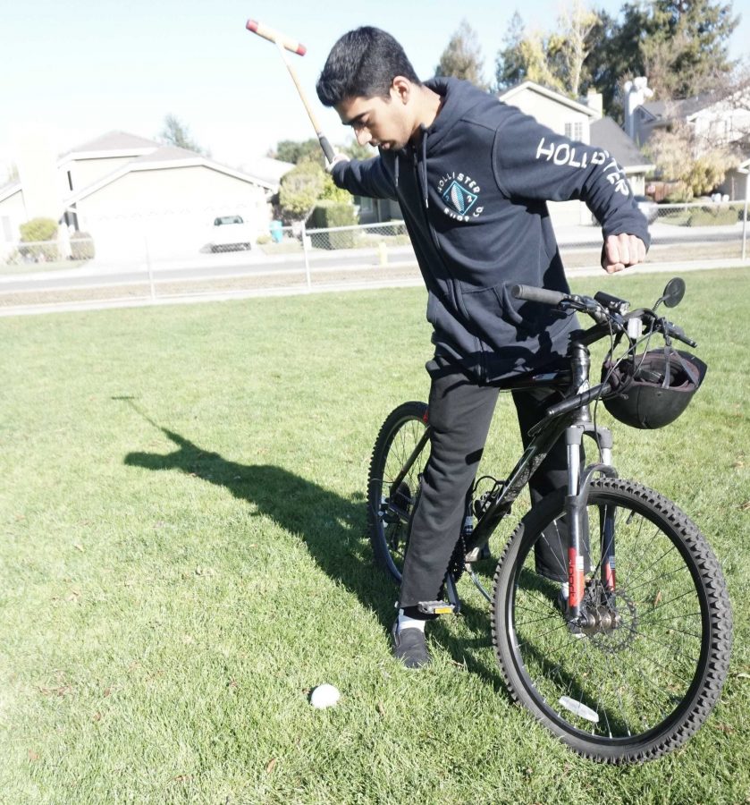 Senior Sid Sharma demonstrates a forehand shot, using his bike as a mock horse. In order to perform shots in polo, Sharma learned how to stand on a galloping horse.