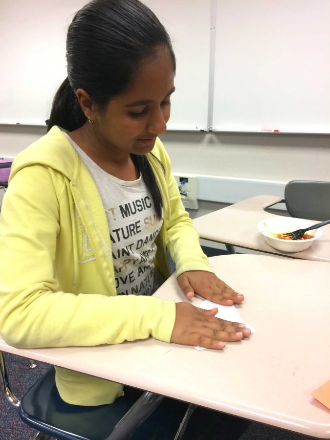 An ArtReach member folds paper in order to make origami. At their first meeting, ArtReach officers explained that making origami art involves no cutting, but rather folding of paper. Photo by Dylan Tsai.
