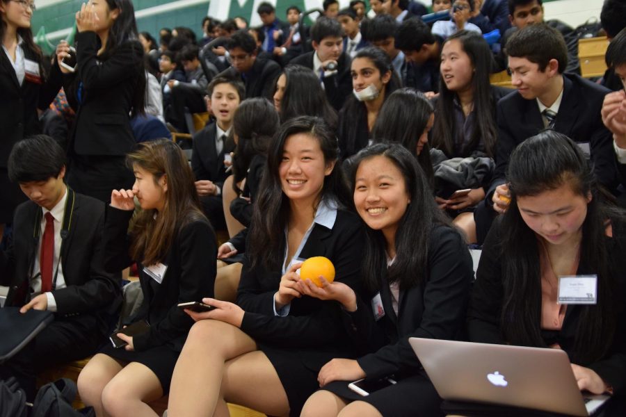 Juniors Emily Su and Theresa Lee pose with an orange. The MVHS chapter gathered in the HHS gym, oranges in hand, hoping for MVHS victories in their competitions. Photo by Om Khandekar