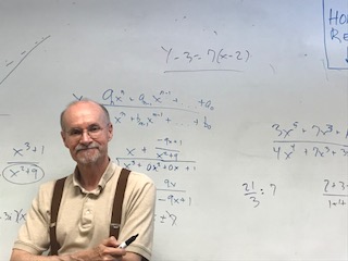 Math teacher Jon Stark stands next to pre calculus equations