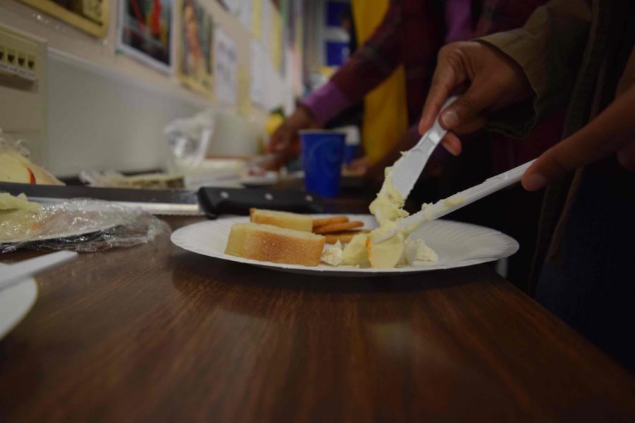  A student puts cheese on her plate. FHS provided crackers and baguettes for students to spread different types of cheese on. Photo by Ilena Peng.