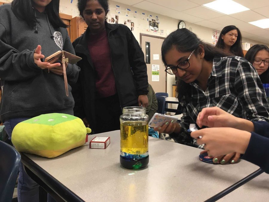 SNHS members gather over a bottle after adding food coloring. The food coloring helps to stain the water when it starts bubbling. Photo by Jennie Chen.