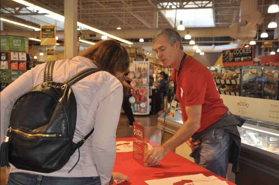 Patrick Wyman informs a customer about the We Love Local event and how to receive a free bag.