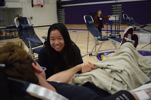 Senior Nate Reyes lies on his seat as he prepares for the procedure while holding on to senior Allison Wu, who smiles at him.