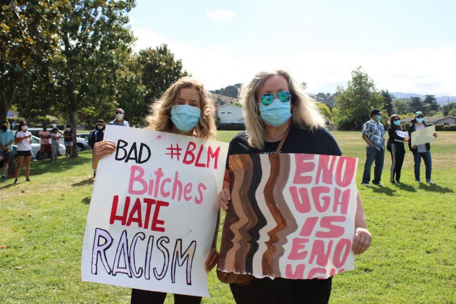 A parent and child hold signs made by themselves at the end of the march. The signs read Bad bitches hate racism and Enough is enough.