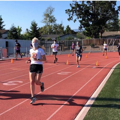 The Cross Country team runs laps around the track, while being socially distant and wearing masks.