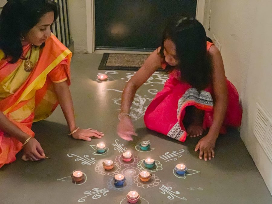 Medha Singamsetty (right) and her mother make rangolis, drawings made with colored sand, outside their house. 