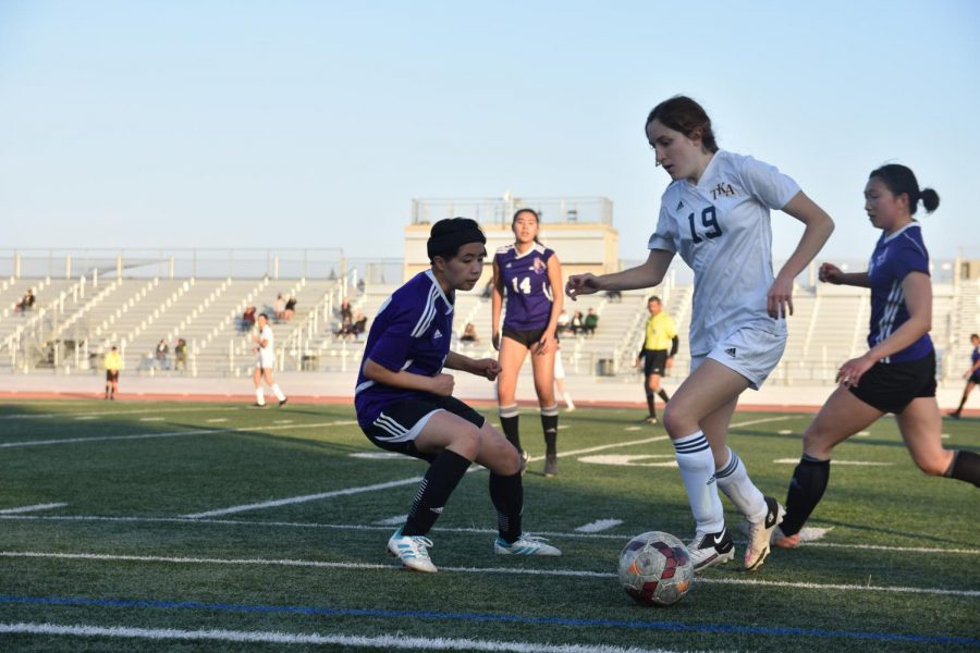 Junior Allison Jiang prepares to steal the ball from a TKA player, using the sideline to restrict the players movement.
