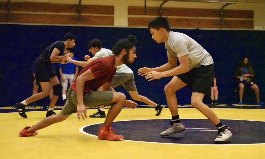 Sophomore Ekom Mann lunges at junior Hayden Ancheta after coach Andrew Pappas signals the wrestlers to “go live” — beginning a practice match that lasts a few minutes. 