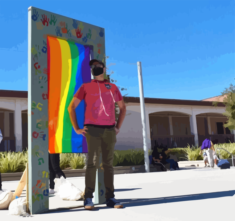 English Teacher Mark Carpenter stands in front of an LGBTQ+ flag. 