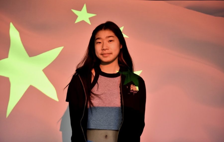 Junior and Varsity Girls Basketball captain Julianna Kimm stands before the Chinese flag.