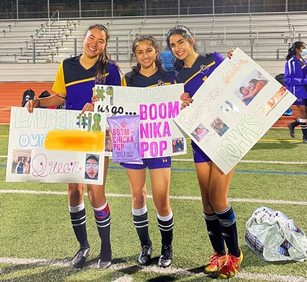 Seniors on the Varsity Girls Soccer team pose with their senior night posters.