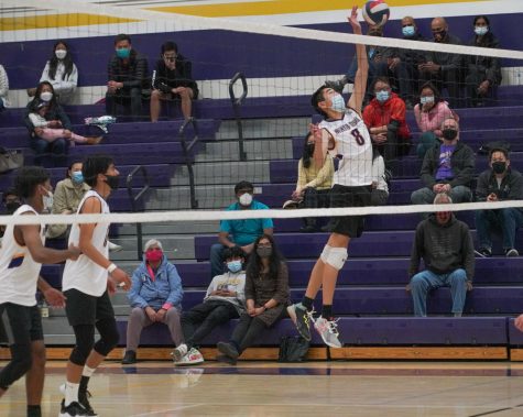 Senior Lance Tong leaps into the air to tip the ball over the net. Photo by Michelle Zheng