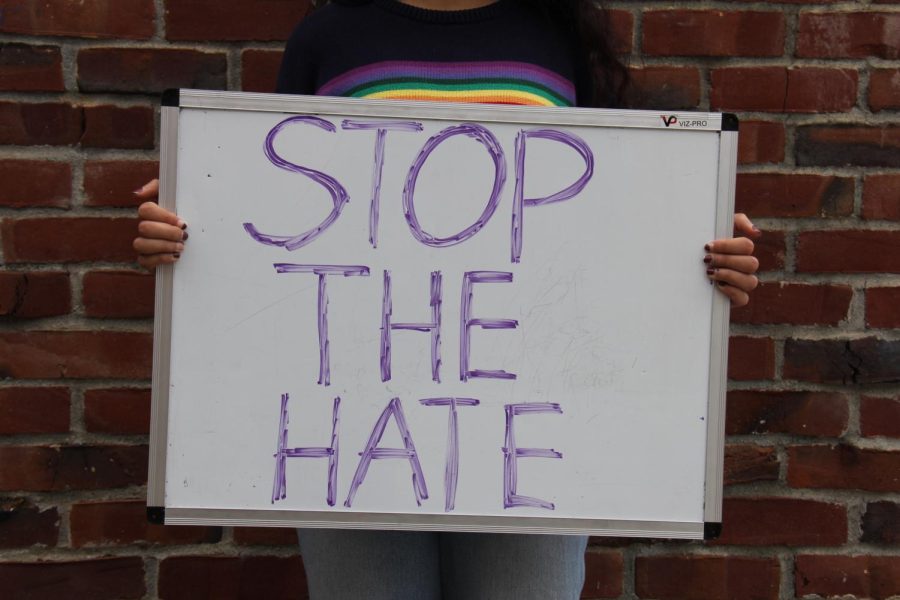 A student hold up a sign reading Stop the Hate to represent to rise of  social justice movements, protesting, and social media in the past few years.