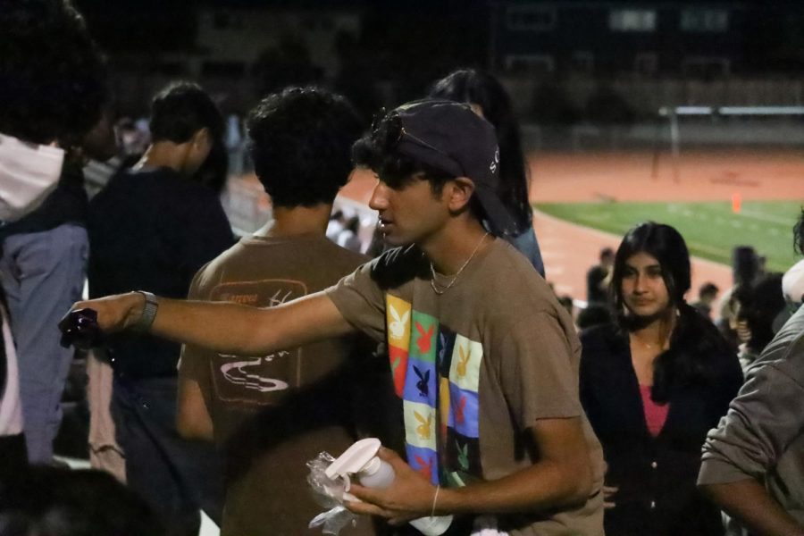 Student Athletic Senate President Rohin Inani hands out MVHS-themed tattoos and lanyards at the football game. 