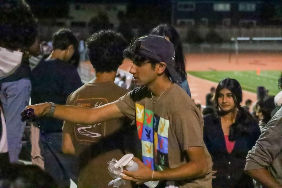 Student Athletic President Rohin Inani hands out MVHS themed lanyards and tattoos at a football game.