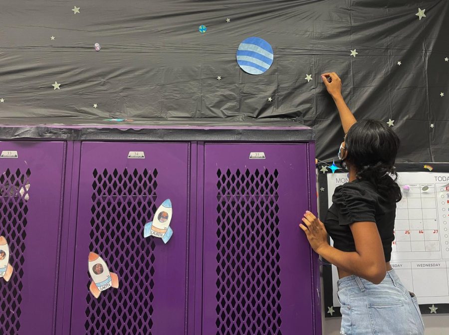 Senior Aashna Patel adds a star to the wall of field hockey‘s space-themed team room. Photo by 