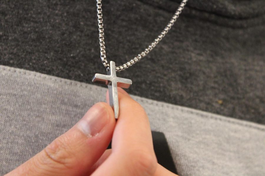 Senior Daniel Yang holds his cross. He wears it every day as a part of his faith. 