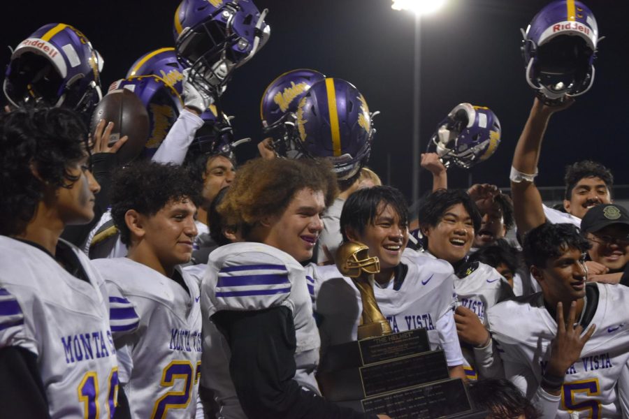 Posing for a celebratory photo, seniors Greyson Mobley and Isaiah Dimaya hold the Helmet trophy while the other team members raise up their helmets.