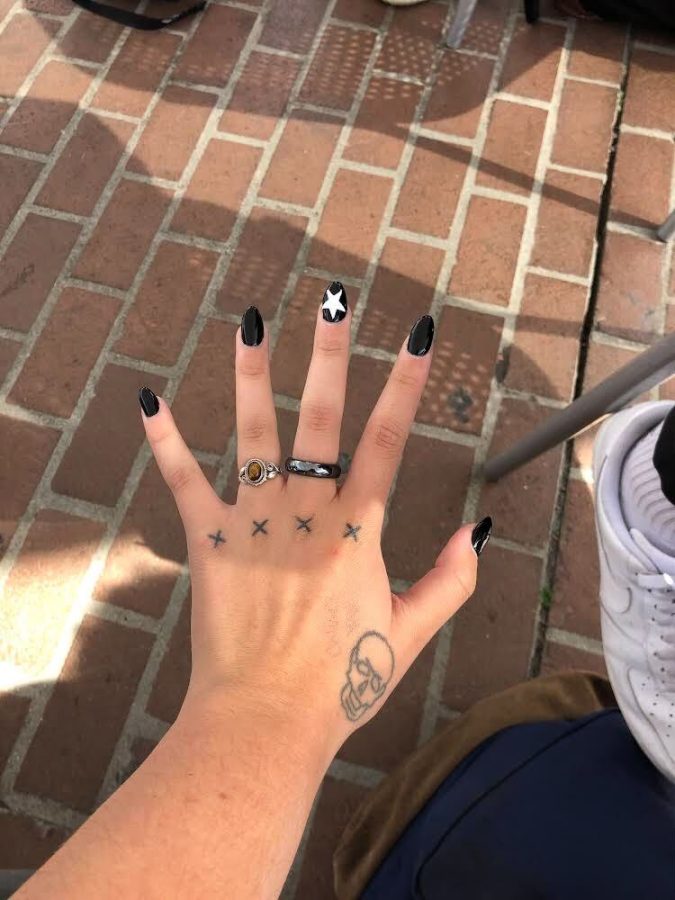 Lisa Smith shows off the multiple stick-and-poke tattoos she did on herself the summer before freshman year, including X’s across her knuckles and a skull. 