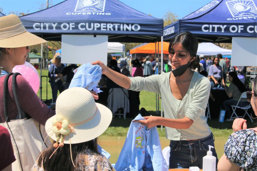Cupertino High School sophomore Lara Gupta hands custom Silicon Valley Youth Climate Action T-shirts to community members.