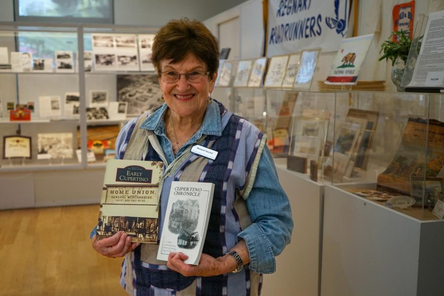 Gail+Fretwell-Hugger+stands+in+the+Cupertino+Historical+Museum+holding+two+books+about+Cupertinos+history.+Photo+by+Alan+Tai