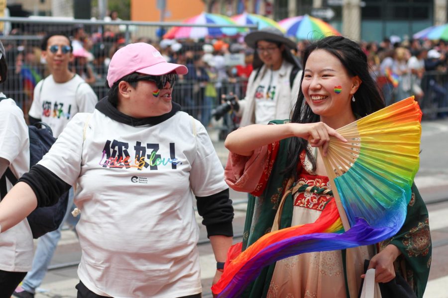 Members of the Chinese Rainbow Network wave rainbow dance fans. 
