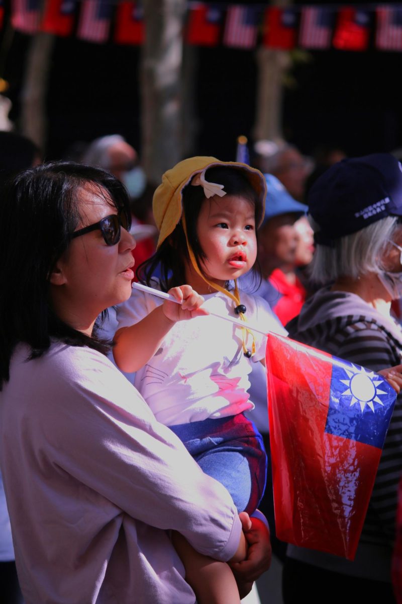 An+attendee+sings+The+National+Anthem+of+the+Republic+of+China+during+the+flag-raising+ceremony+while+holding+a+child.