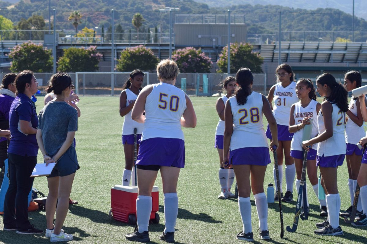 De Leon and Yoo (both on far left) huddle with the Varsity Field Hockey team, discussing strategies for the game against Wilcox High School on Sept. 11. Photo | Lily Jiang