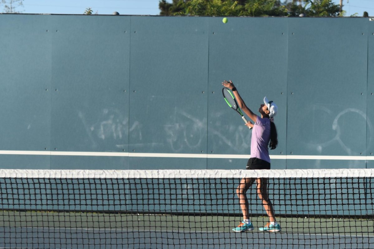 Senior Himani Jha shifts her weight backward and throws the ball up before serving. 