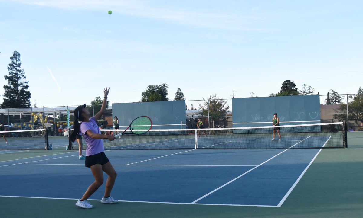 Sophomore Jillian Yang arches her body as she gets ready to serve to her opponent in a doubles match.  