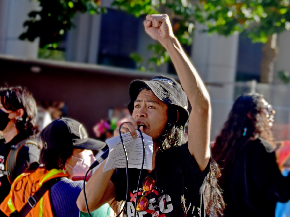 An activist in San Francisco speaks into a microphone, protesting the 2023 APEC summit. Photo Courtesy of Ann Penalosa / La Voz News