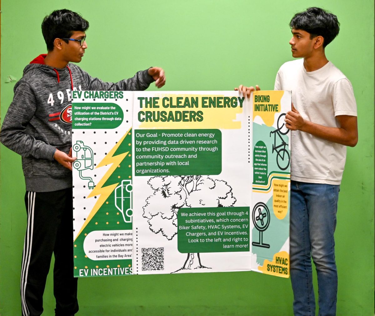 Batchu and Kulkarni hold their poster board, depicting their various clean energy initiatives.