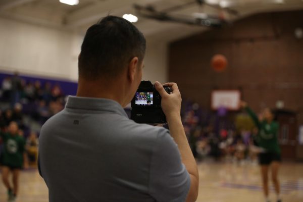 Freelance photographer John Ling looks into his camera as he attempts to take a picture of a jumping athlete.