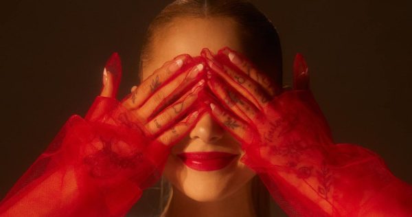 One of the eternal sunshine album covers features Ariana Grande in sheer red gloves, covering her eyes with a smile on her face. Album cover | Republic Records