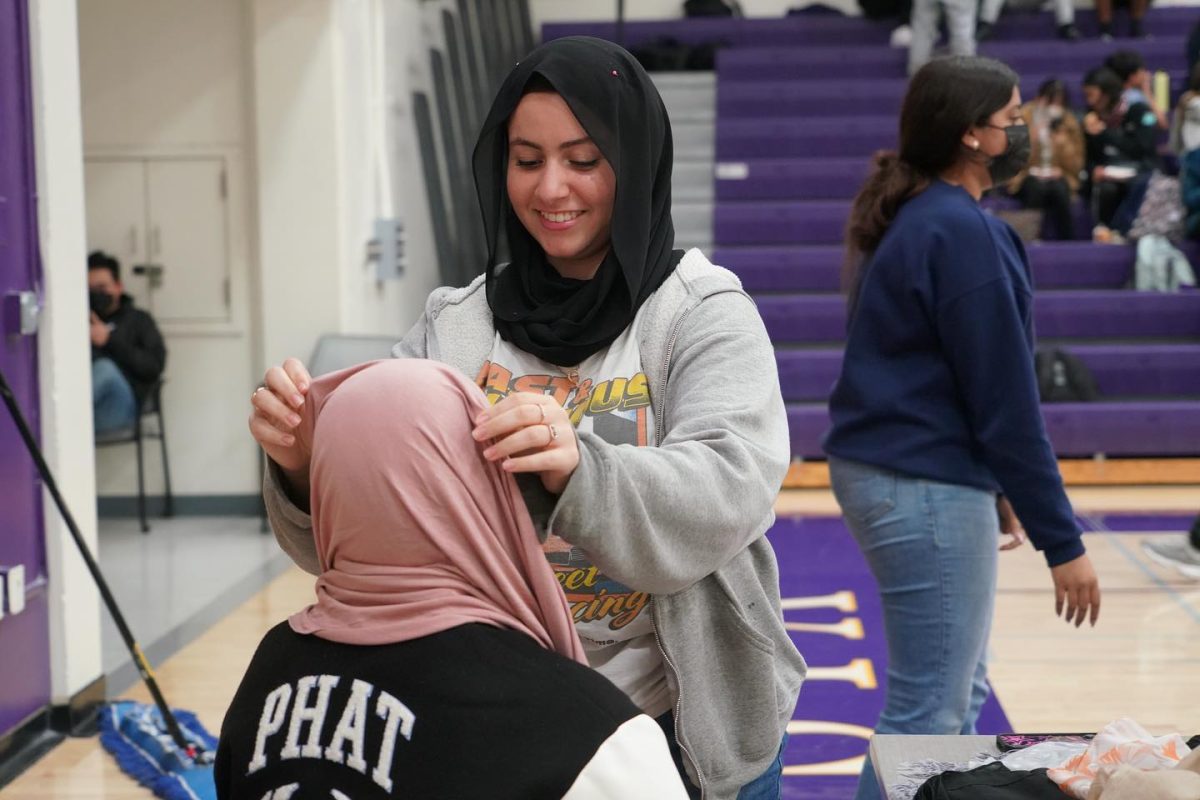 Senior Aya Abdelrahman fits a hijab on a student. | Photo by Michelle Zheng