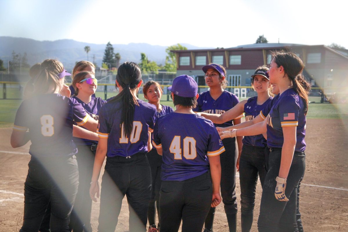 The softball team huddles up for a cheer after the game.