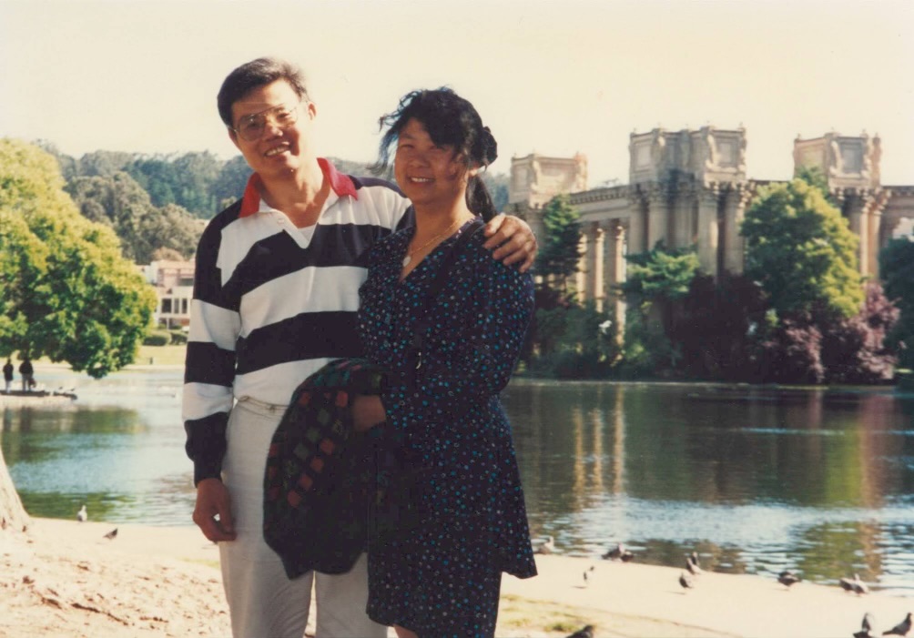 Shi Tong Huang and Qi Jie Yang smile for a photo in front of a lake. 