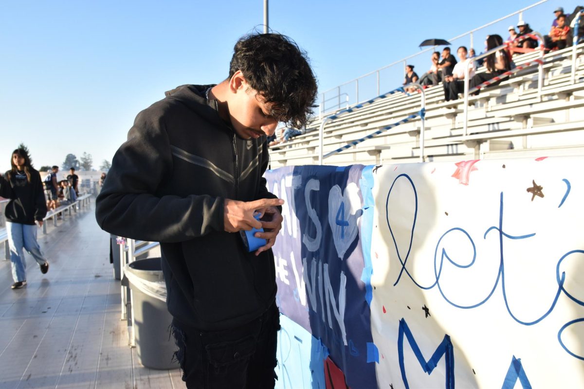 Junior and spirit commissioner, Yuvan Kothari tapes together posters at the front of the bullpen.