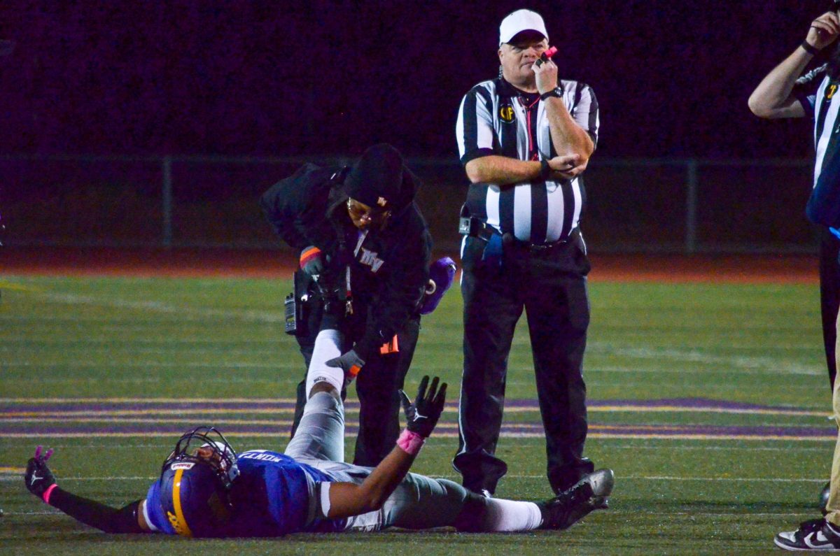 Athletic Trainer and Health Clerk Myesha Taylor helps stretch junior Kingston Jourdan during the football game against Lynbrook High School on Oct. 24