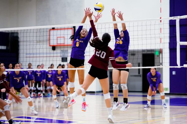 Senior and middle hitter Samantha Tong works with freshman and outside hitter Tracy He to block the ball from an opposing player.
