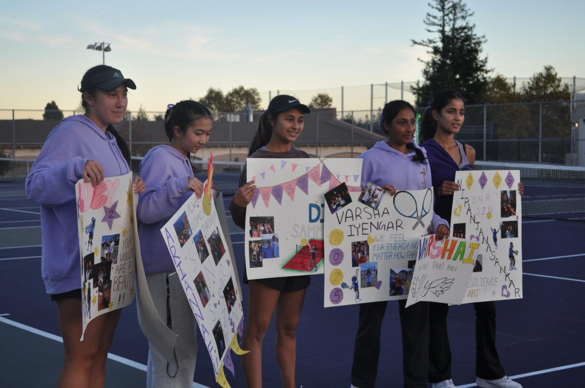 Seniors on the tennis team pose with their Senior Night posters